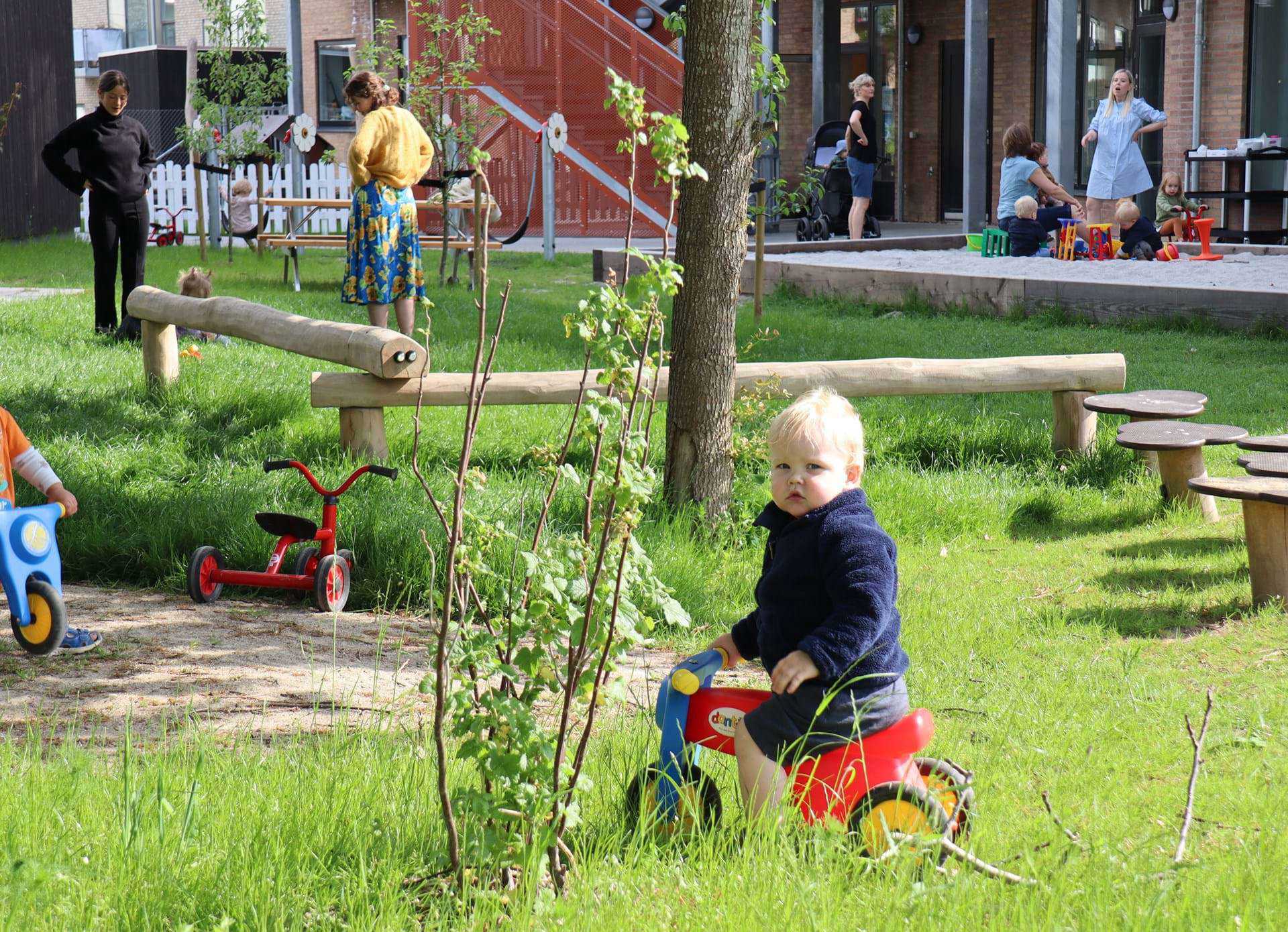 Dreng på scooter i græsset på legepladsen ved Kongevellen